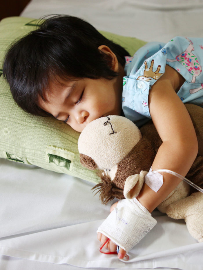 child sleeping in hospital with stuffed animal