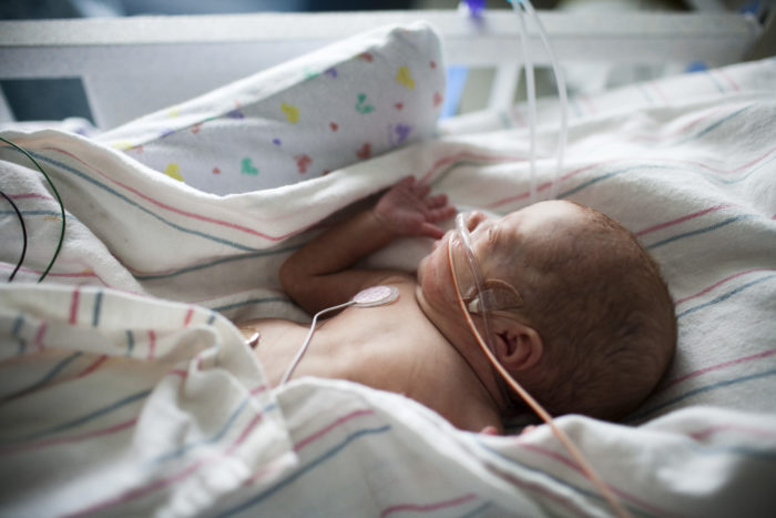 Newborn in crib, in the neonatal intensive care unit