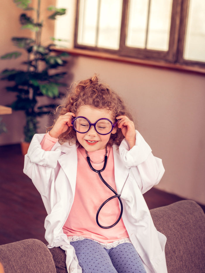 young girl with glasses playing doctor