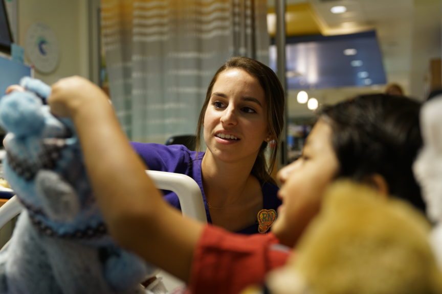 A nurse and patient play with a stuffed animal.