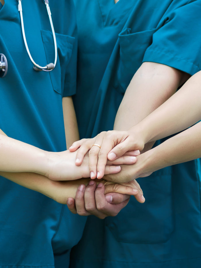 doctors and nurses putting their hands together like a team