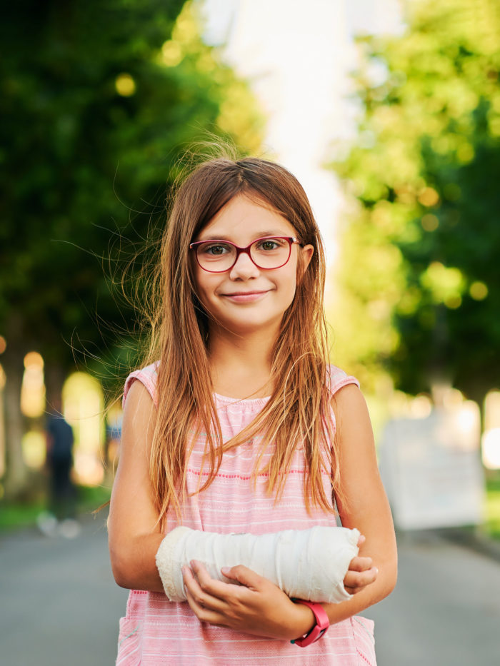 Outdoor portrait of sweet little girl with a cast