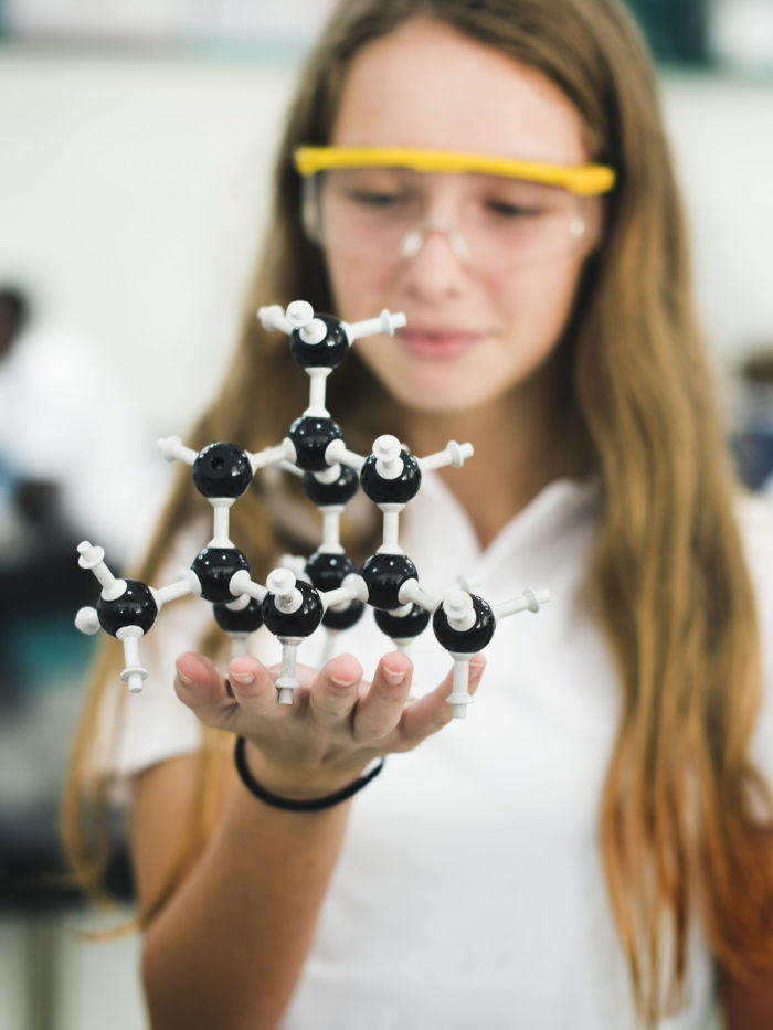 High school student hand holding molecule structure in chemistry class