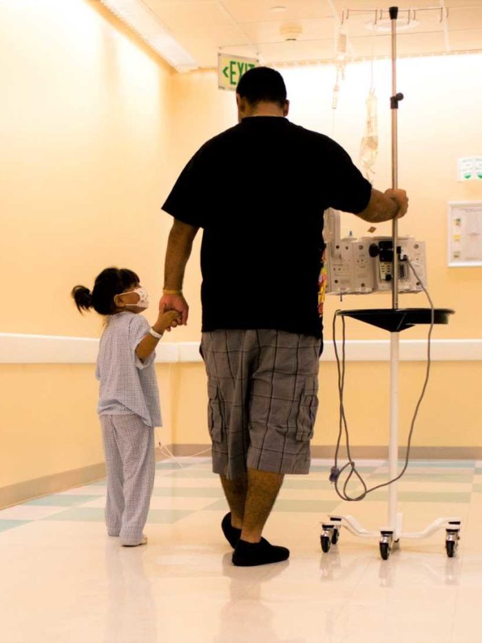 Child cancer patient and father walk through hospital