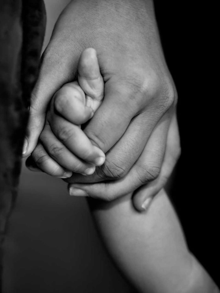 Child and adult holding hands in black and white
