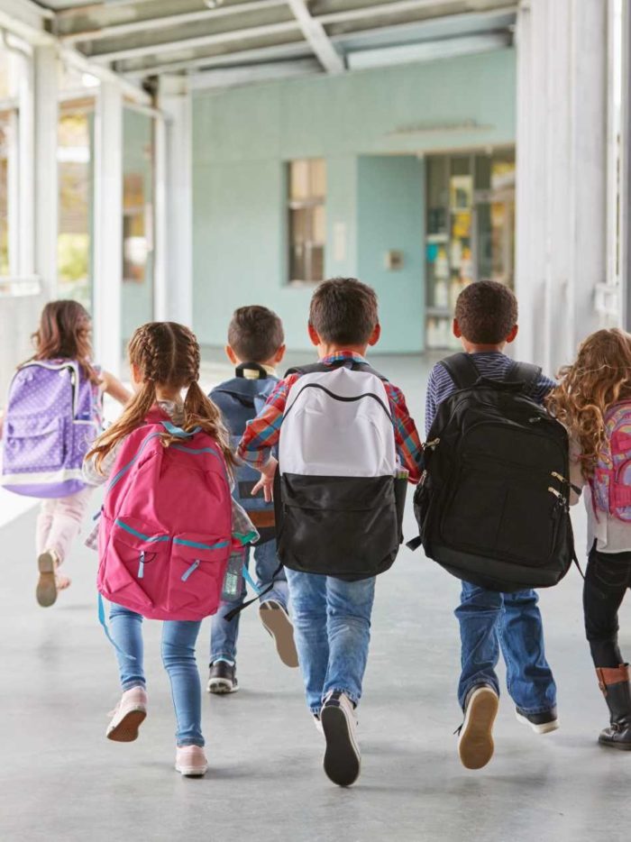 Children with backpacks running at school