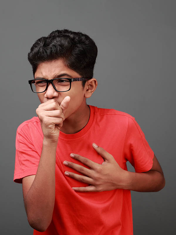 boy coughs and covers his mouth with his hands