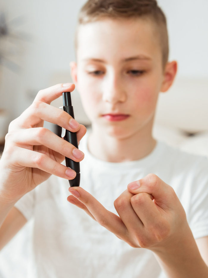 Teen boy takes a blood sample for diabetes