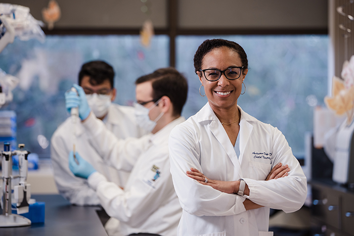 woman smiles in research lab with researchers in the background