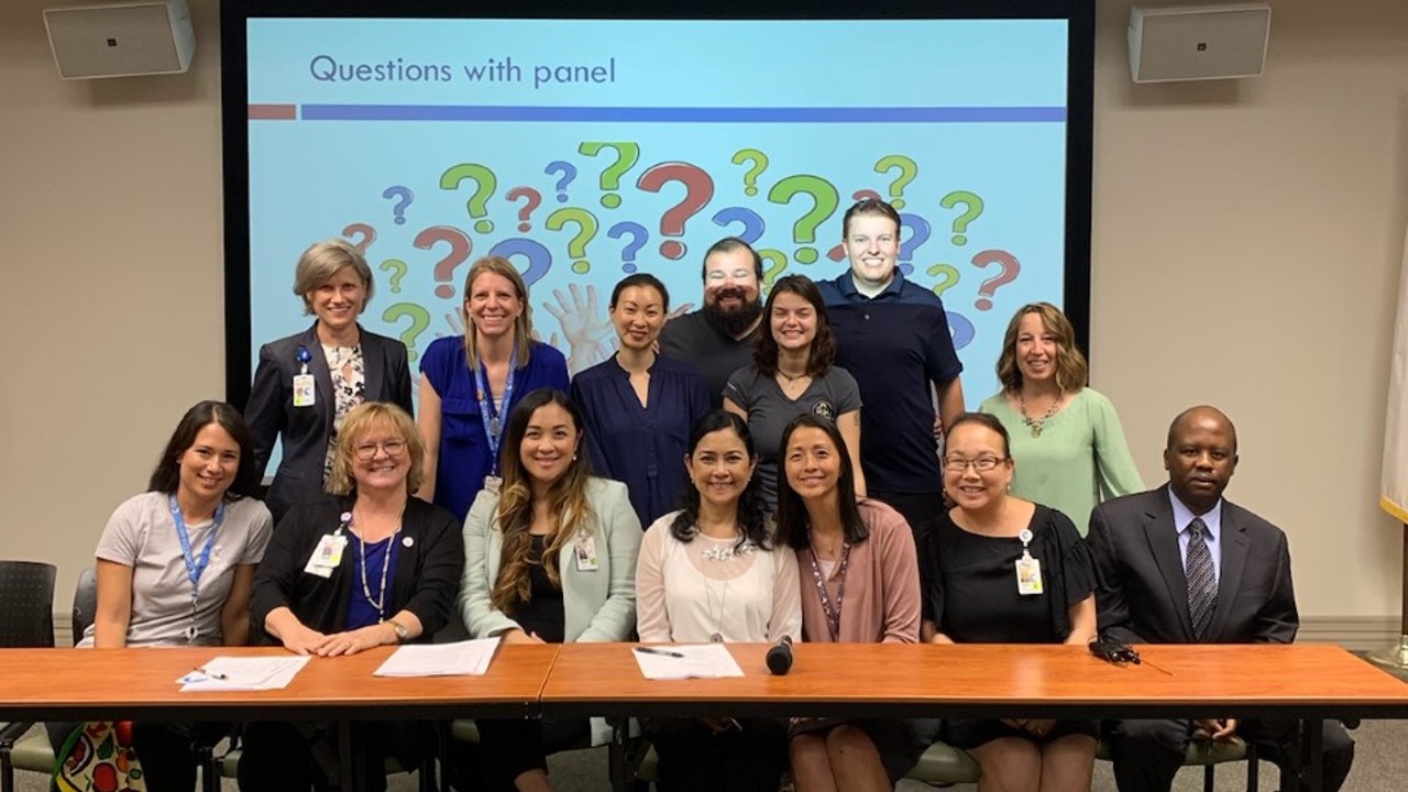 Group of doctors smile for a group photo during a panel discussion 
