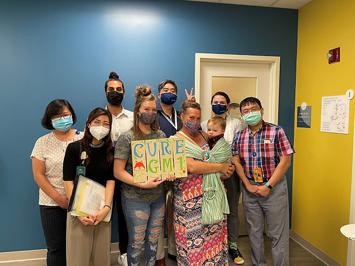 Bentley's family with Dr. Wang's team at CHOC pose together with a "Cure GM1" sign. 