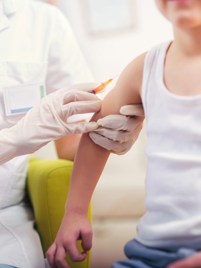 image of a boy's arm receiving a vaccine from a doctor