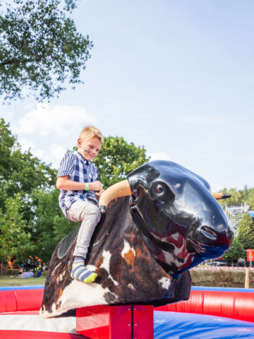 Boy riding mechanical bull outside