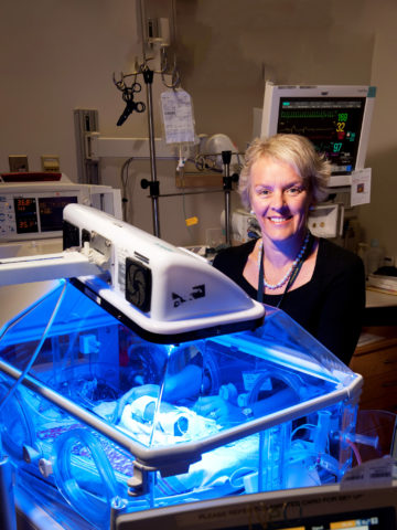 Dr. Terri Inder standing beside a NICU incubator