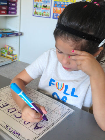 Camilia practices writing the alphabet while wearing her cochlear implants