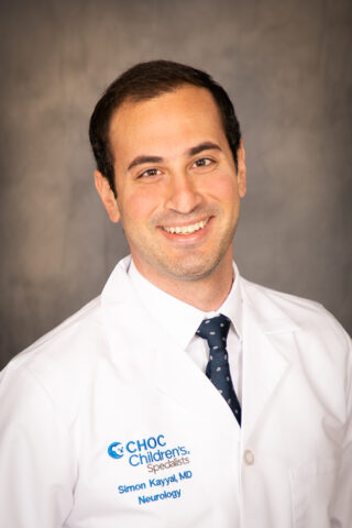 Man in lab coat and tie smiles - headshot of Dr. Simon Kayyal  