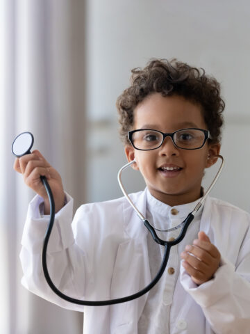 Child dressed up like doctor looks into the camera and smiles