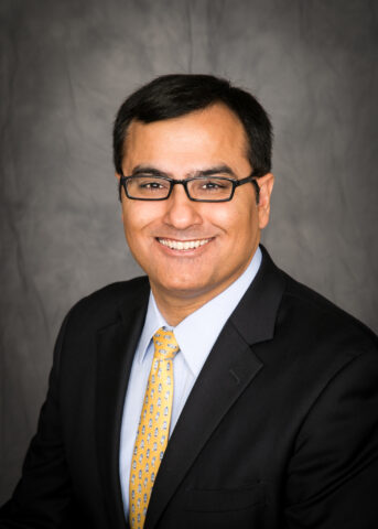 Headshot of man in suit wearing glasses - Dr. Amit Soni