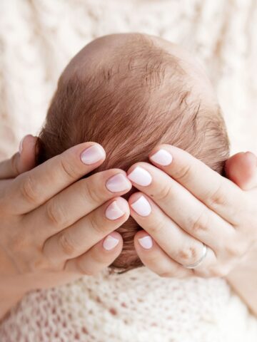 adult hands cradle a baby's head