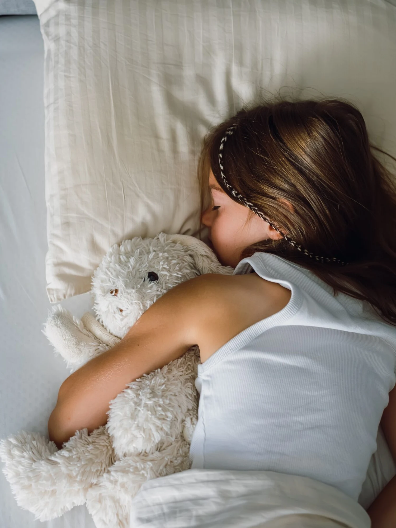 a young girl peacefully sleeping on her side holding a bunny stuffie